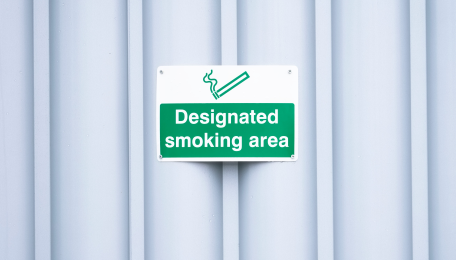 A green sign that says “Designated smoking area” with the image of a cigarette.