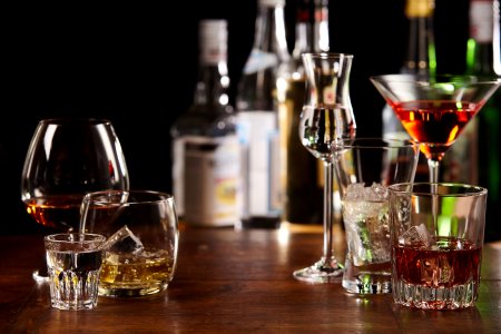 A photo of drink glasses filled with different colored alcoholic beverages.
